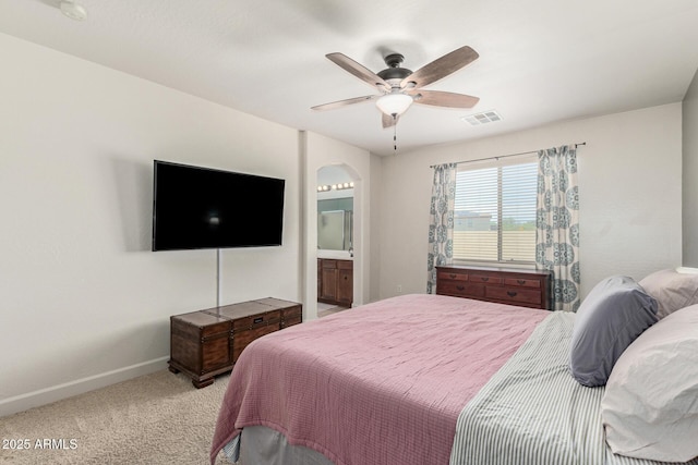 157 N 110th Ave, Avondale, AZ 85323 - bedroom featuring baseboards, light colored carpet, arched walkways, ceiling fan, and connected bathroom