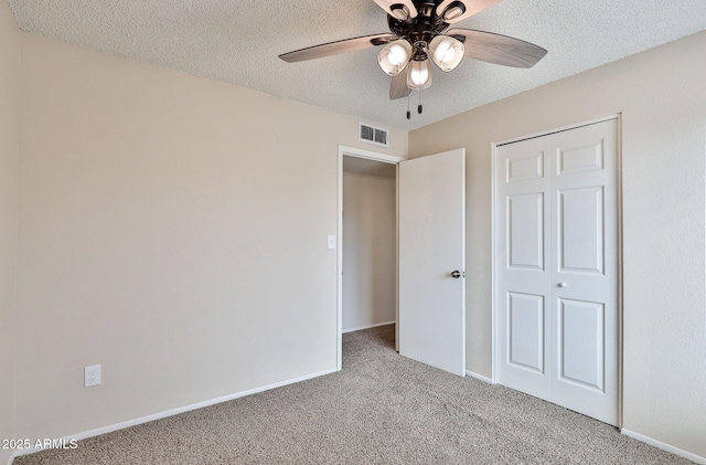 unfurnished bedroom featuring ceiling fan, light carpet, and a textured ceiling