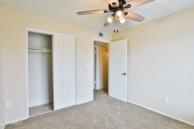 unfurnished bedroom featuring ceiling fan, light colored carpet, a closet, and a textured ceiling