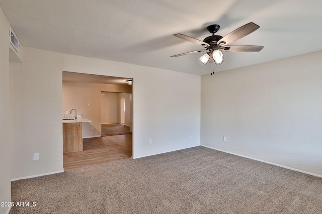 unfurnished room with ceiling fan, carpet flooring, sink, and a textured ceiling