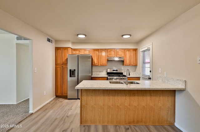 kitchen featuring sink, decorative backsplash, kitchen peninsula, stainless steel appliances, and light wood-type flooring