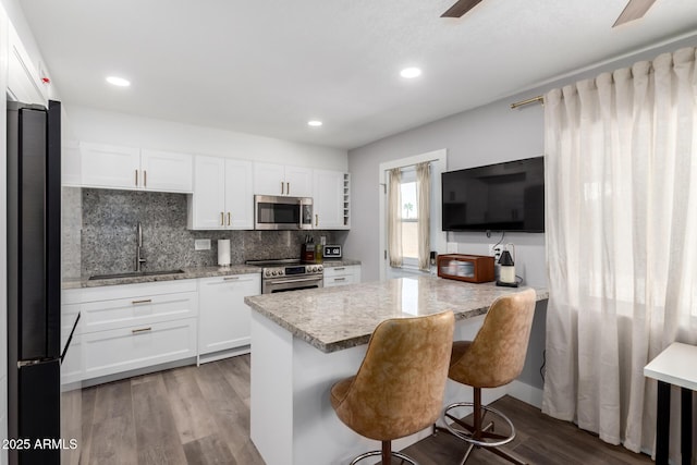 kitchen featuring backsplash, dark wood finished floors, stainless steel appliances, and a sink