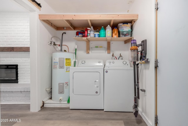 laundry area featuring laundry area, wood finished floors, washing machine and clothes dryer, a brick fireplace, and water heater