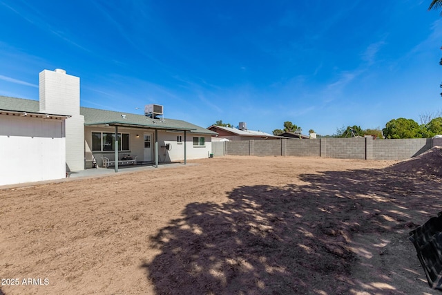 rear view of property with cooling unit, a fenced backyard, a patio, and a chimney