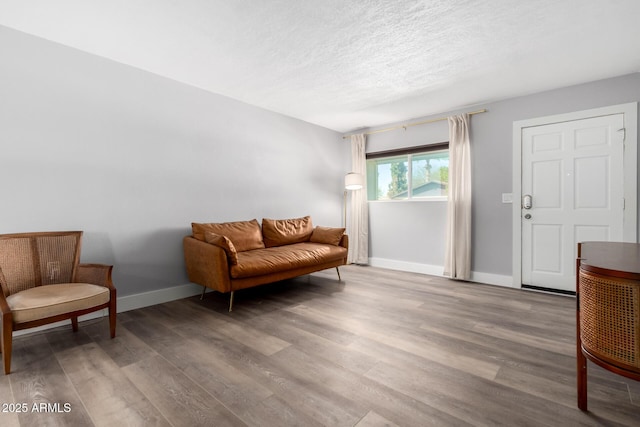 sitting room with a textured ceiling, baseboards, and wood finished floors