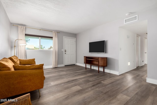 living room with baseboards, visible vents, and wood finished floors