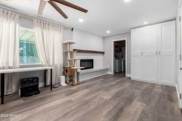 living area with a fireplace, separate washer and dryer, wood finished floors, and recessed lighting