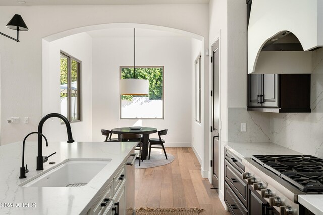 kitchen with sink, appliances with stainless steel finishes, light stone counters, and light hardwood / wood-style floors