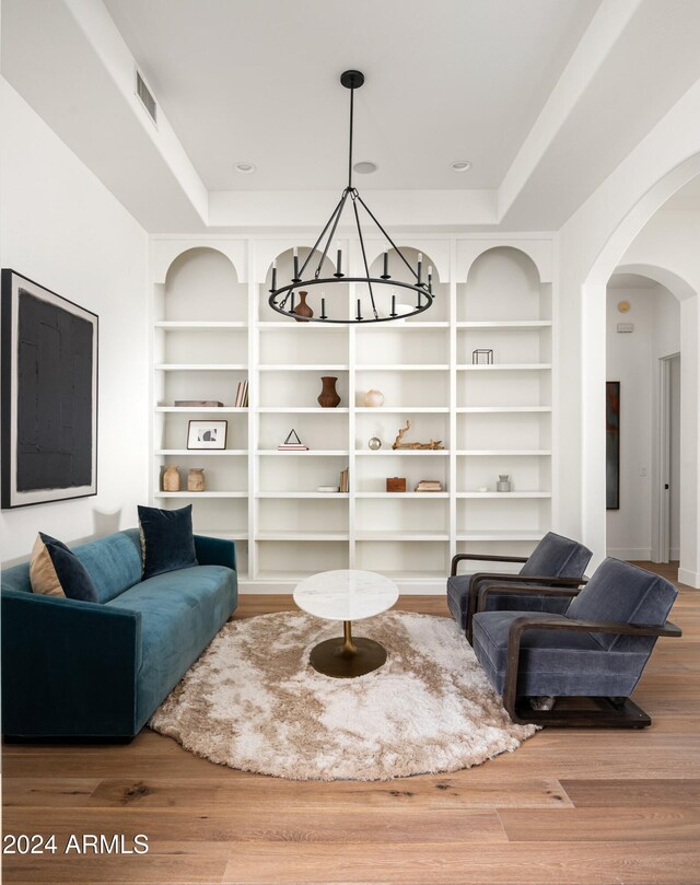 living room featuring built in features, a chandelier, and hardwood / wood-style floors