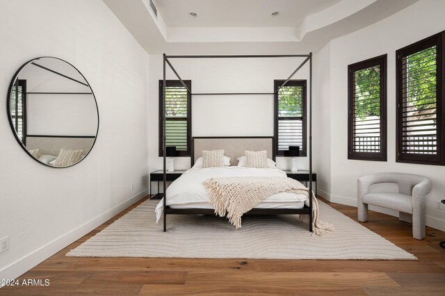 bedroom with wood-type flooring and a tray ceiling