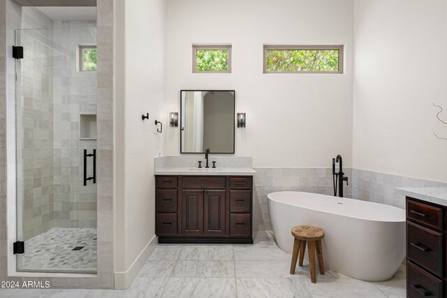 bathroom with vanity, independent shower and bath, and tile walls