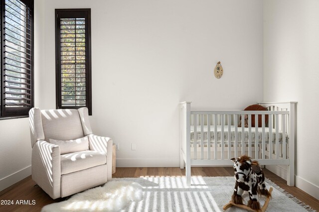 bedroom featuring hardwood / wood-style floors and a nursery area