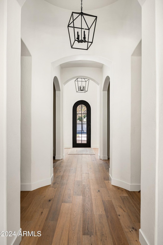 hall with a chandelier and wood-type flooring