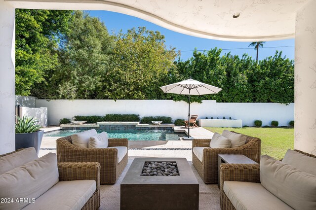 view of patio / terrace with a fenced in pool, pool water feature, and an outdoor living space with a fire pit