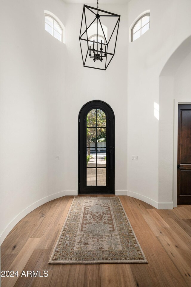 foyer featuring a towering ceiling, light hardwood / wood-style flooring, and a chandelier