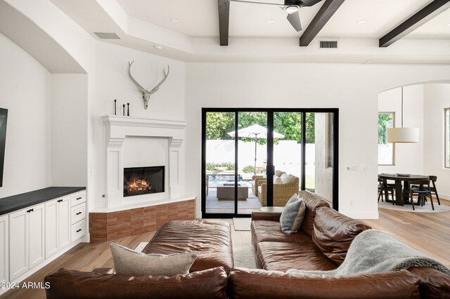 living room with ceiling fan, beamed ceiling, and light hardwood / wood-style flooring