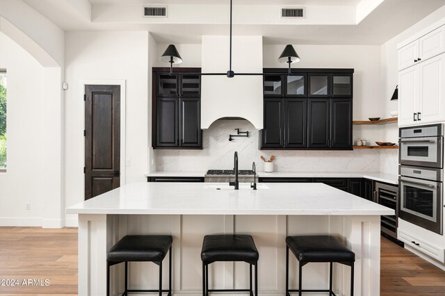 kitchen with a center island with sink, a kitchen bar, and hardwood / wood-style flooring