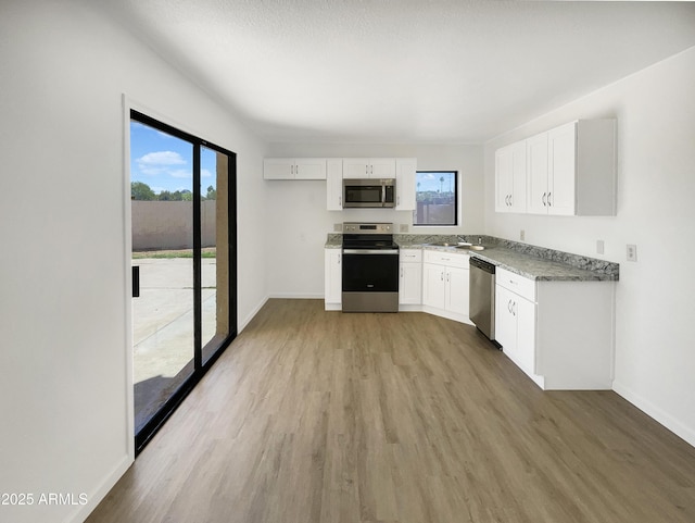 15650 N 19th Ave Unit 1206, Phoenix, AZ 85023 - kitchen featuring stainless steel appliances, plenty of natural light, white cabinetry, and light wood finished floors