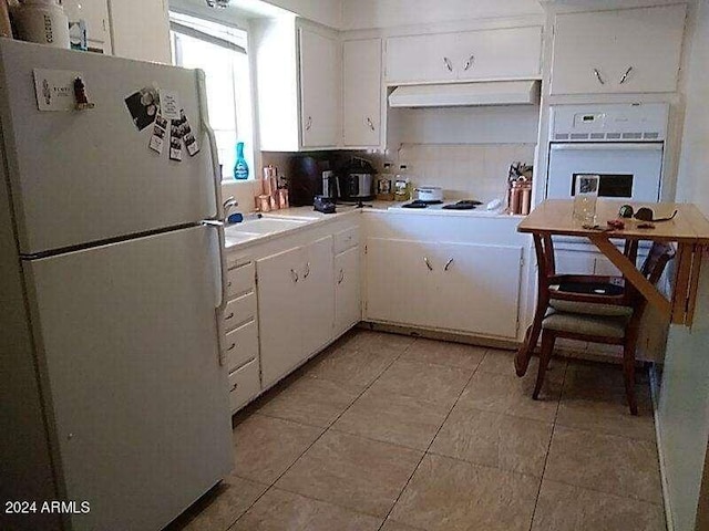 kitchen with backsplash, white appliances, white cabinetry, and light tile patterned flooring