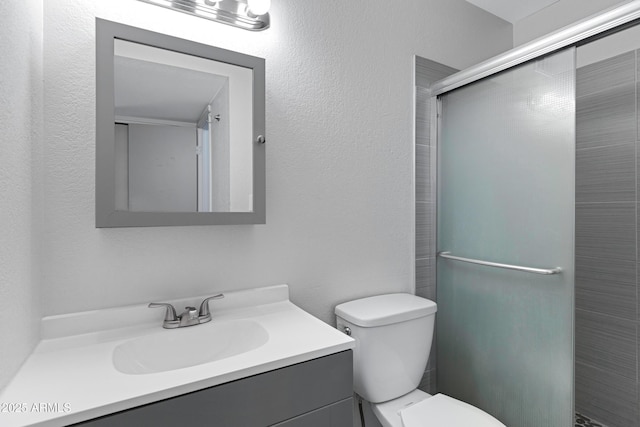 bathroom featuring toilet, a shower with shower door, and vanity