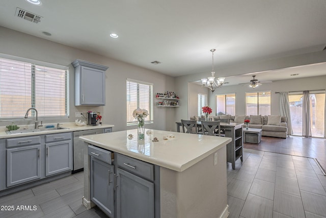 kitchen with gray cabinets, a wealth of natural light, sink, hanging light fixtures, and a center island