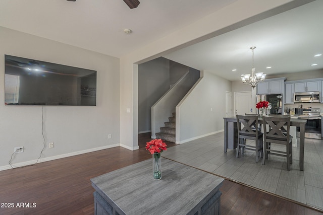 dining space with ceiling fan with notable chandelier and dark wood-type flooring