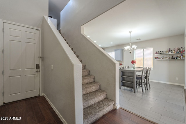 staircase featuring hardwood / wood-style flooring and an inviting chandelier