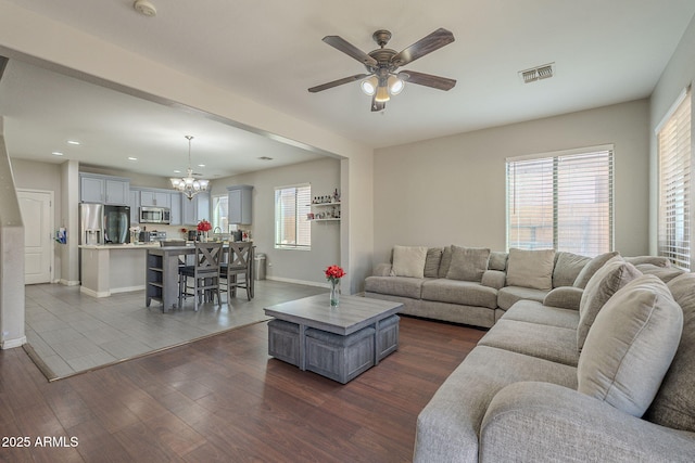 living room featuring ceiling fan with notable chandelier and dark hardwood / wood-style flooring