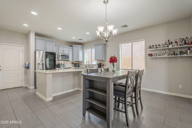 kitchen with pendant lighting, sink, appliances with stainless steel finishes, gray cabinetry, and a center island