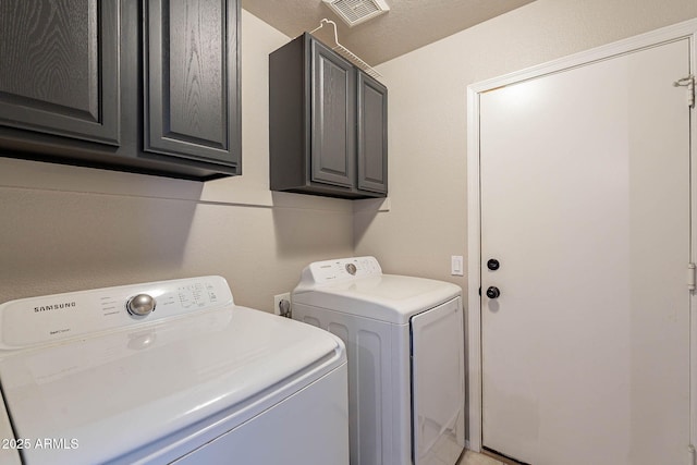 laundry room featuring visible vents, cabinet space, and separate washer and dryer