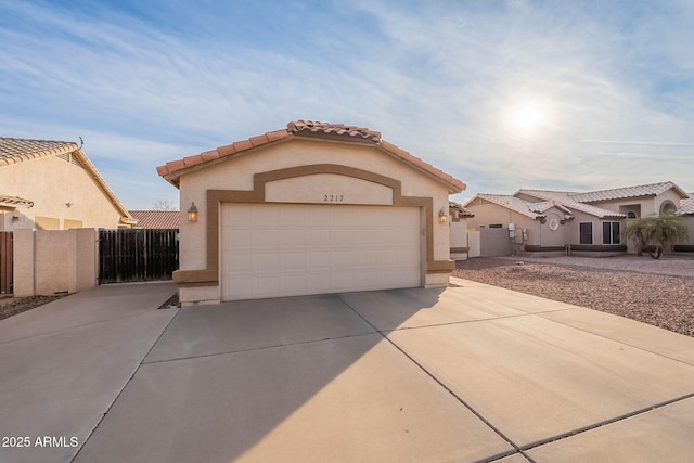 mediterranean / spanish-style home with concrete driveway, fence, a tiled roof, and stucco siding