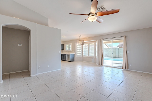 unfurnished room with arched walkways, light tile patterned floors, visible vents, ceiling fan, and a sink