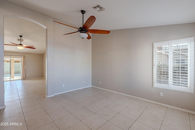 unfurnished room with light tile patterned floors, visible vents, arched walkways, baseboards, and ceiling fan