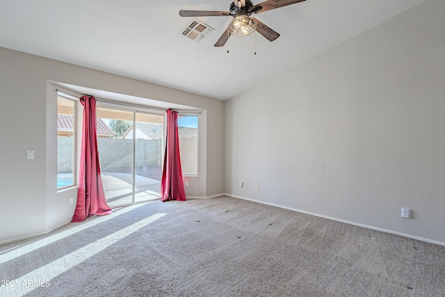 carpeted spare room with lofted ceiling, a ceiling fan, visible vents, and baseboards