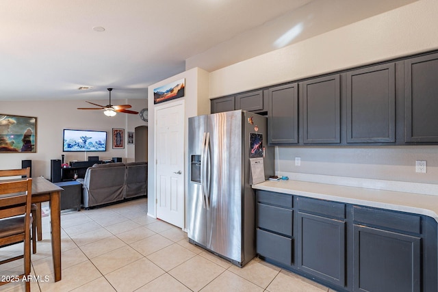 kitchen featuring light tile patterned floors, stainless steel fridge, arched walkways, a ceiling fan, and lofted ceiling