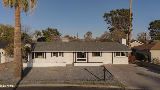 ranch-style house featuring stucco siding, roof with shingles, and fence