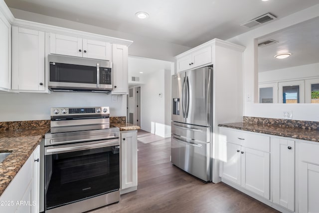 kitchen featuring visible vents, white cabinets, stainless steel appliances, and wood finished floors