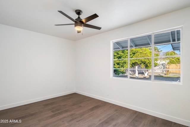 unfurnished room featuring dark wood finished floors, a ceiling fan, and baseboards