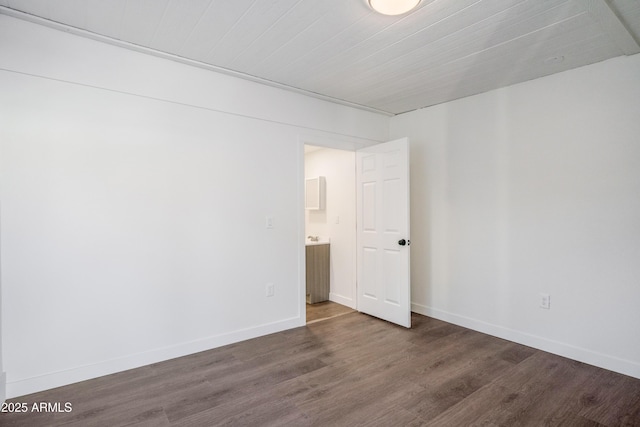 spare room with baseboards and dark wood finished floors