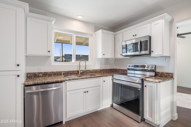 kitchen with a sink, appliances with stainless steel finishes, dark wood-style floors, and white cabinets