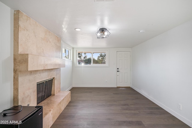 unfurnished living room with visible vents, baseboards, dark wood-style floors, and a high end fireplace