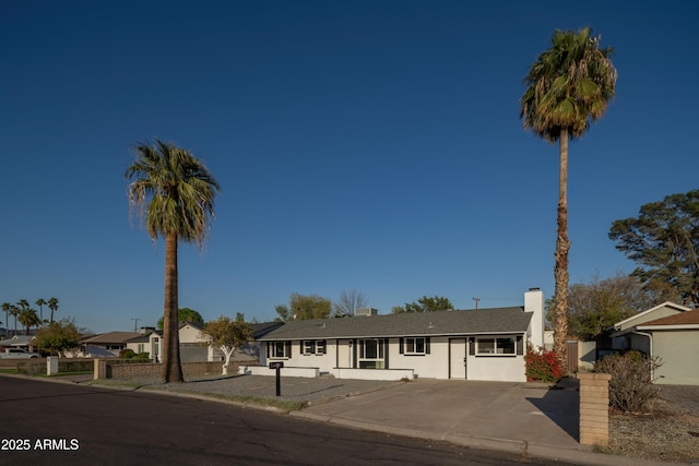 ranch-style house featuring a chimney and fence