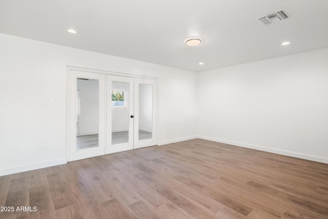 spare room featuring visible vents, baseboards, recessed lighting, french doors, and wood finished floors