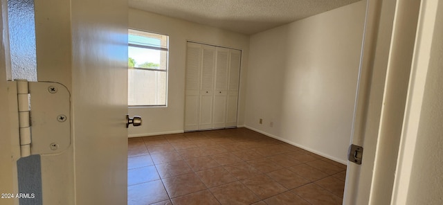 unfurnished room featuring tile patterned flooring and a textured ceiling