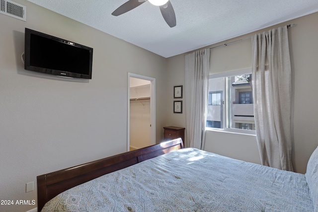 bedroom featuring a textured ceiling, a closet, a spacious closet, and ceiling fan