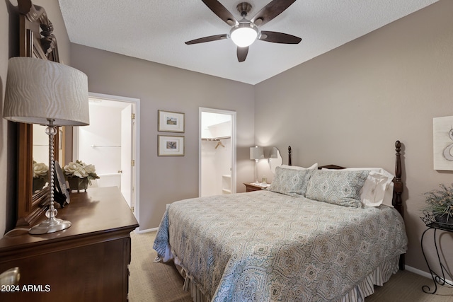 carpeted bedroom featuring a walk in closet, ceiling fan, a closet, and a textured ceiling