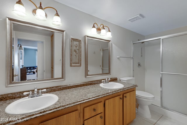 bathroom featuring toilet, vanity, tile patterned floors, and a shower with shower door