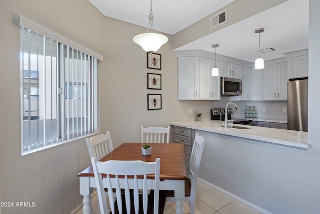 kitchen featuring light stone countertops, appliances with stainless steel finishes, pendant lighting, and light tile patterned flooring