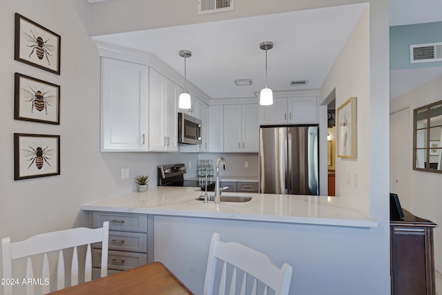 kitchen featuring white cabinets, hanging light fixtures, sink, appliances with stainless steel finishes, and kitchen peninsula