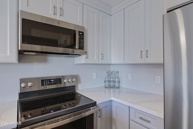 kitchen with stainless steel appliances, white cabinetry, and light stone counters